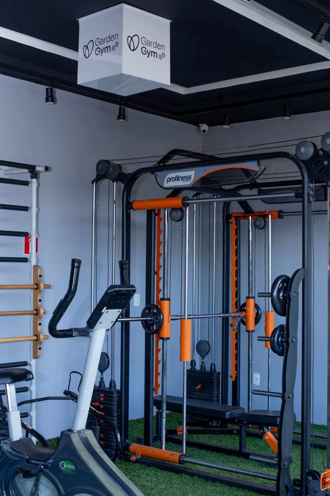 Vista geral da academia do hotel com estação de musculação, esteira e equipamentos de cardio.